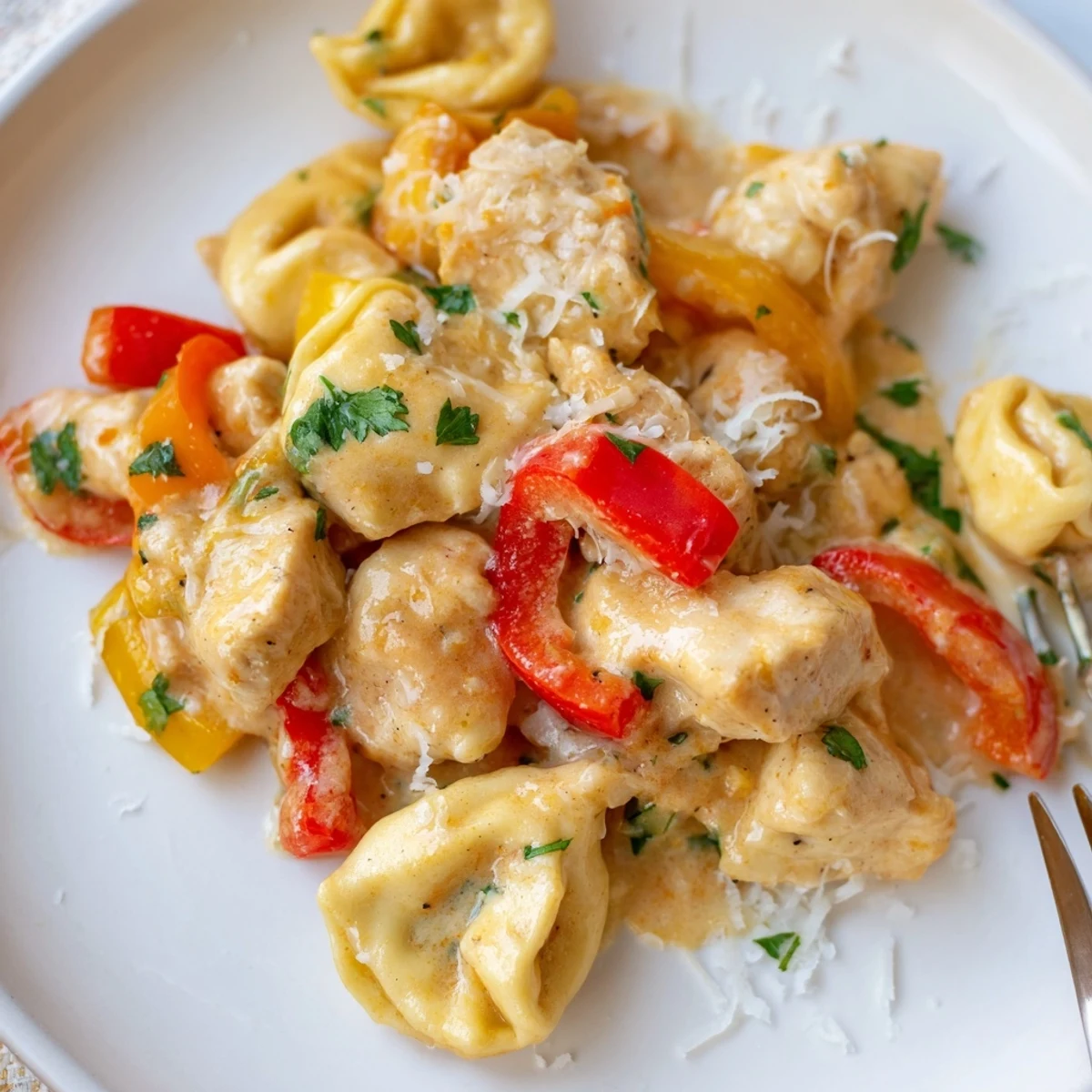 A vibrant plate of Zesty Cajun Garlic Parmesan Chicken Tortellini garnished with fresh parsley.  