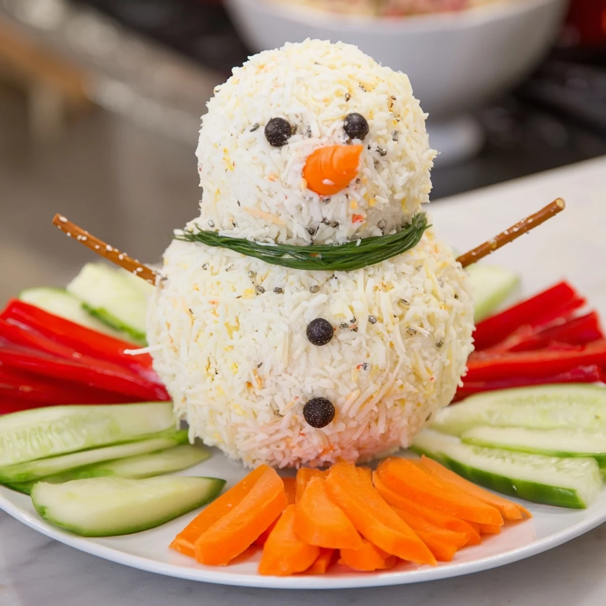 Creamy Savory Herb Cheeseball Snowmen are decorated with carrot noses, peppercorn eyes, and chive scarves.