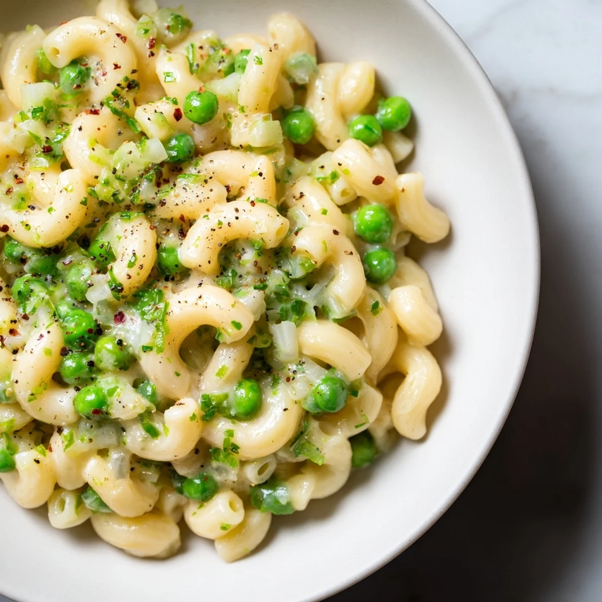 Steaming bowl of macaroni & peas, coated in a light sauce, ready for a quick dinner.