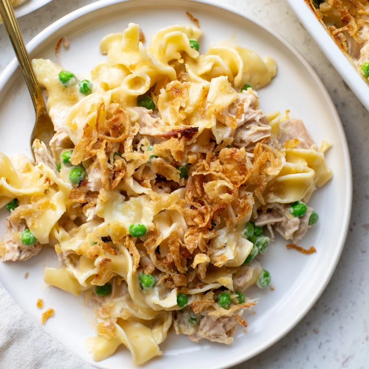 This warm photo reveals a creamy tuna noodle casserole with a crispy, buttery onion topping served.
