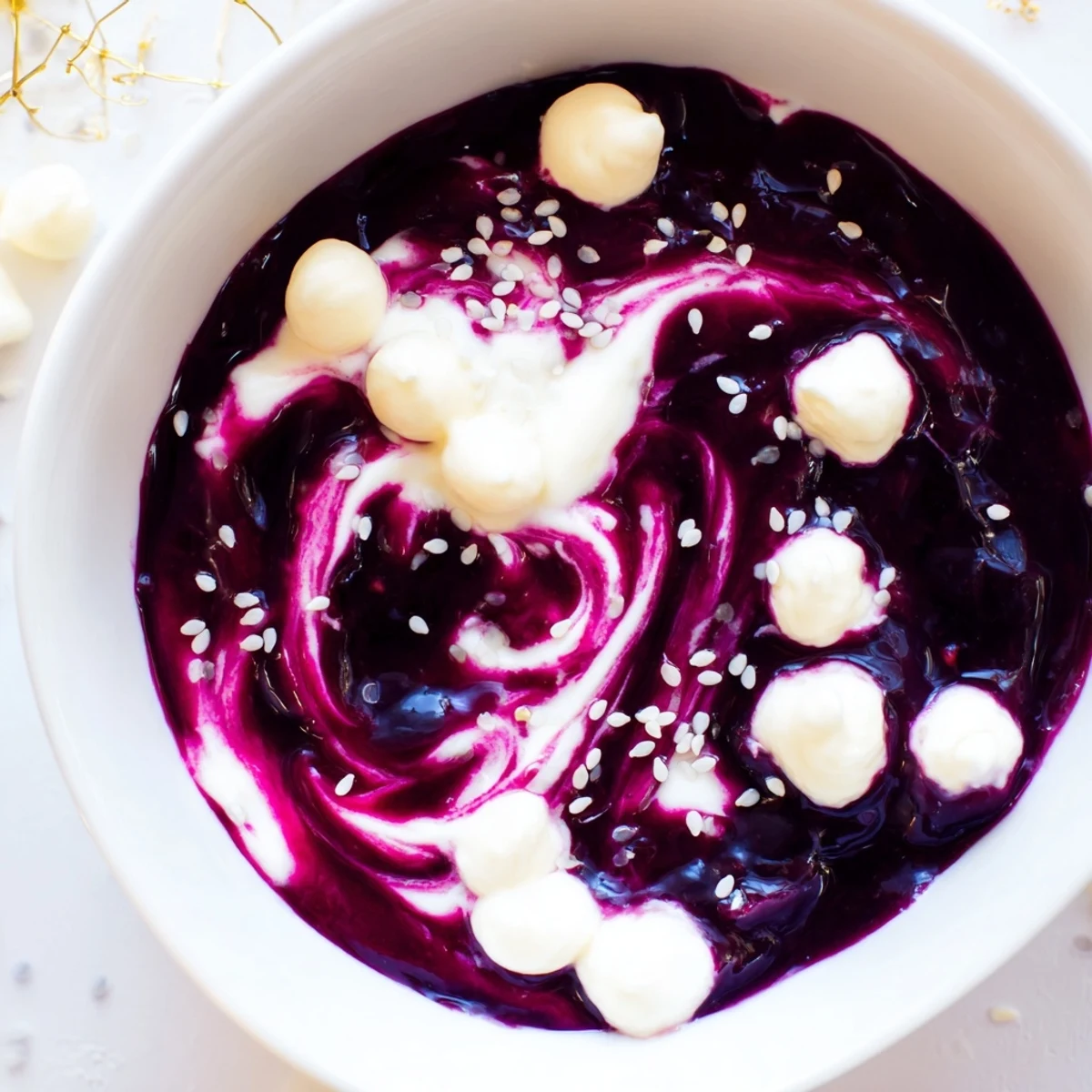 Beautiful Galaxy Spiral dessert swirls dark berry jam into creamy yogurt, sprinkled with sesame seeds.