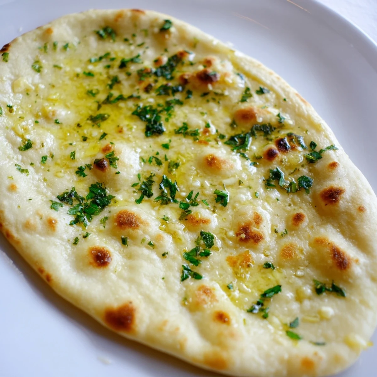 Fluffy homemade garlic naan bread brushed with garlic butter—a warm, savory Indian flatbread delight.