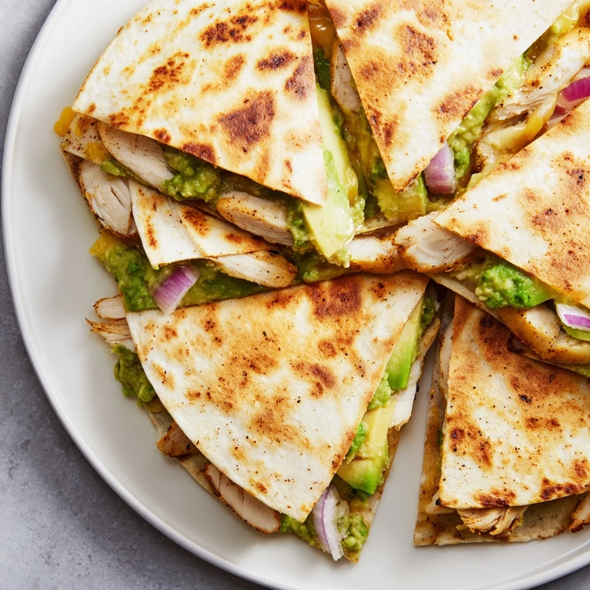 A close-up of a delicious Chicken Avocado Quesadilla, with visible grilled chicken and fresh avocado.