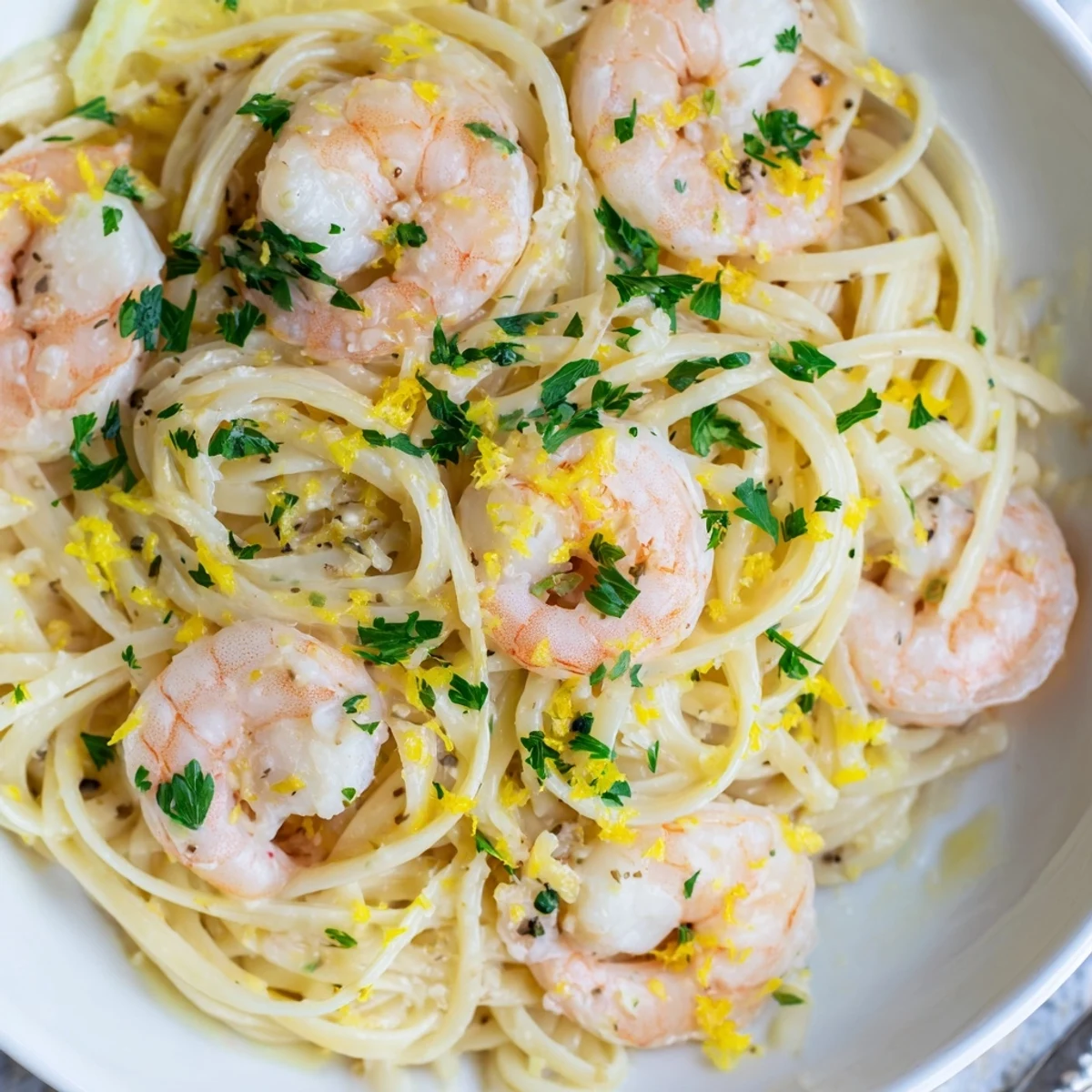Plated Shrimp Scampi With Linguine brightened by lemon zest and parsley, served with lemon wedges and a glass of white wine.