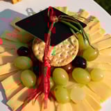 Delicious Graduation Cap Platter, offering a festive spread with grapes, cherry tomatoes, and Gouda cheese cubes.
