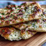 Golden-brown Best Easy Garlic Naan Bread fresh from the skillet, brushed with melted butter and minced garlic.