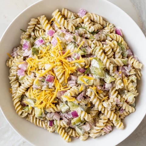 Close-up view of creamy Dill Pickle Pasta Salad with fresh dill and cheddar cheese visible.