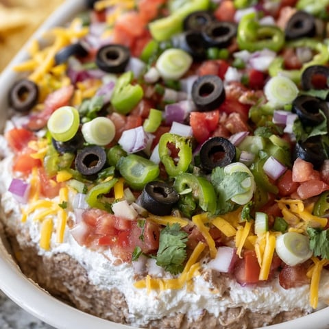 Freshly made 4-Way Layered Dip with vibrant layers of beans, creamy cheese, chunky salsa, and colorful toppings.  