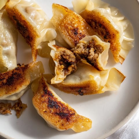 Golden-bottomed smash dumplings sizzling in a skillet with a crispy, crunchy exterior.