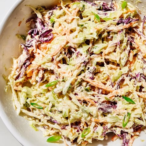 Freshly made Best Cabbage Coleslaw featuring crisp shredded cabbage and carrots in creamy dressing, ready for a barbecue plate.