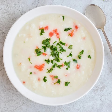 A bowl of creamy White Bean Soup with Tomato garnished with fresh basil and a swirl of olive oil.