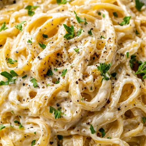 A close up of a bowl of pasta with cheese and herbs.