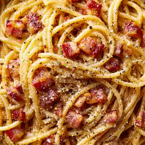 A close up of a plate of spaghetti with bacon.