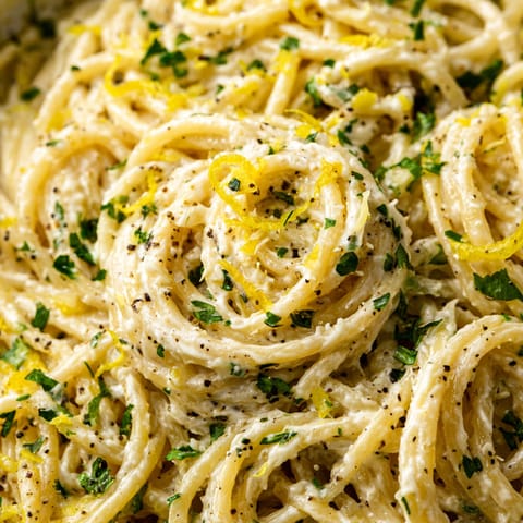 A bowl of spaghetti with a lemon wedge on top.