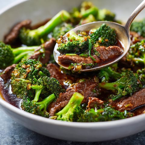 A bowl of beef and broccoli with a spoon in it.
