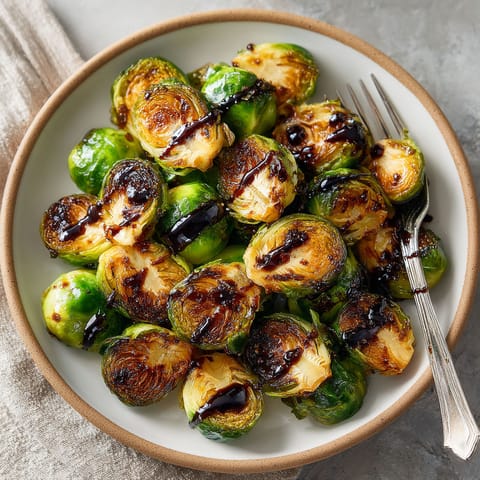A plate of cooked brussel sprouts with a fork on the side.