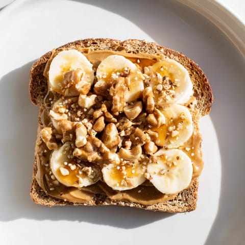A layered peanut butter & banana sandwich upgrade, delicious with honey drizzle and fresh banana slices.