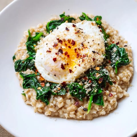 A close-up of savory oatmeal topped with spinach, a runny egg, ready to eat.