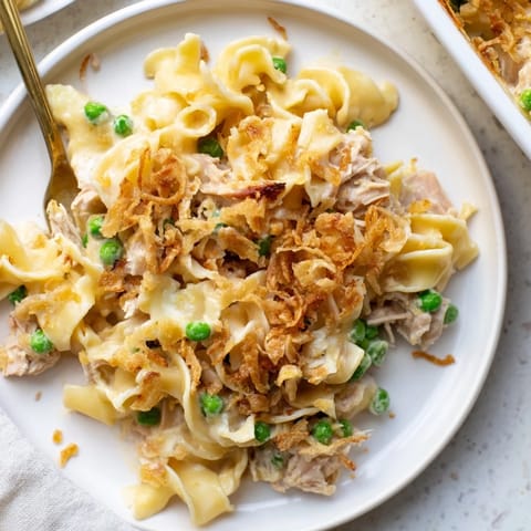 This warm photo reveals a creamy tuna noodle casserole with a crispy, buttery onion topping served.