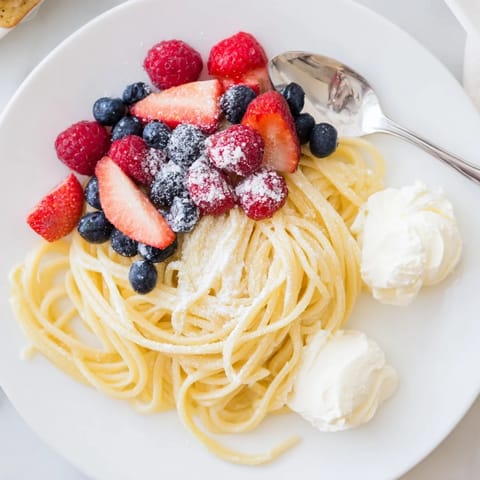 Quick Festive Pancake Spaghetti, a whimsical brunch dish with fresh berries and powdered sugar.