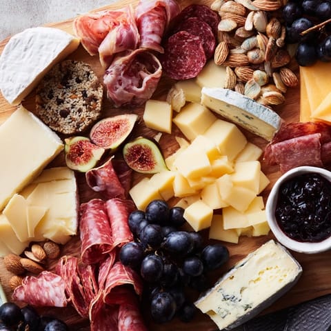 This Wine & Food Pairing Platter features a selection of cheeses, fruits, and meats, ready to enjoy.