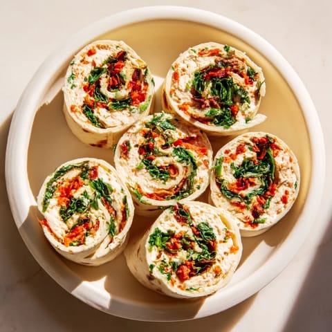 Holiday appetizer of Christmas Scarf Tortilla Roll-Ups sliced and arranged like a scarf, filled with creamy flavors.