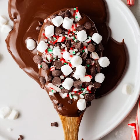 Decadent hot chocolate spoon toppings board, boasting colorful marshmallows, crunchy peppermint, and chocolate chips.