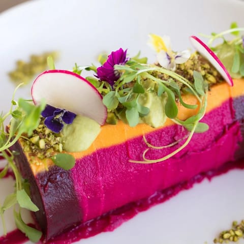 Close-up of the Modernist Stripe appetizer: layers of colorful vegetables creating an artistic stripe design.