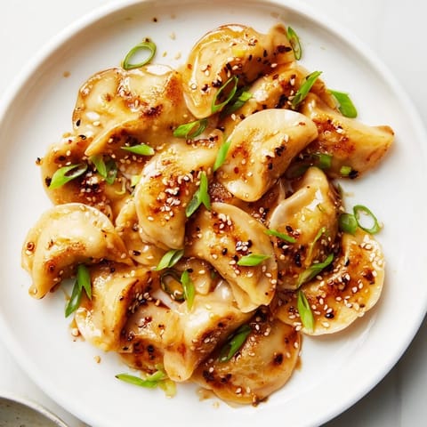 Tender, pan-fried air fryer frozen dumplings, served hot with sesame seeds and green onions, ready to eat.