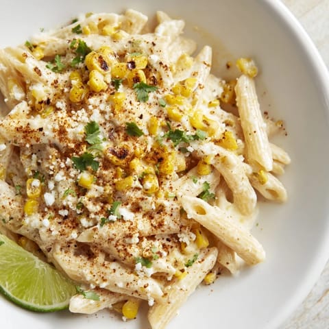 This Mexican street corn pasta showcases a bowl of pasta with corn, cheese, and fresh cilantro.