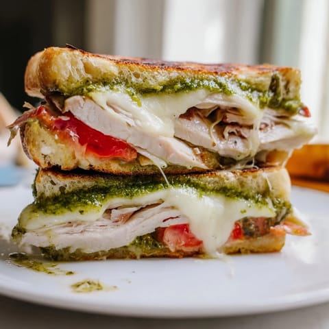 Warm, grilled Chicken Pesto Panini, showing a close-up of the melty cheese and juicy chicken filling.