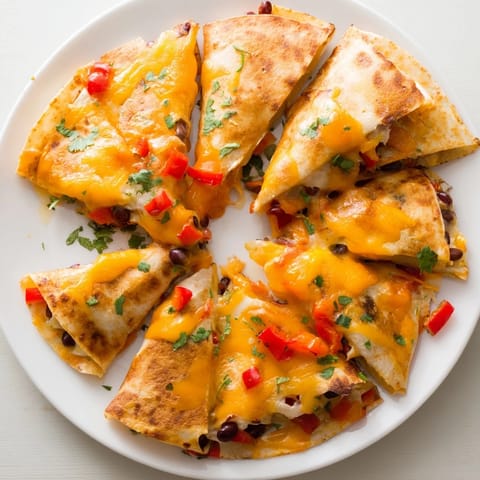 Fresh diced bell peppers and black beans peek through the crispy tortilla triangles of this vegetarian Blooming Quesadilla Ring, garnished with cilantro and lime wedges.  