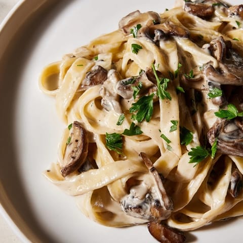 Close-up of Creamy Mushroom Stroganoff, highlighting the luscious sour cream sauce, umami-rich mushrooms, and a dusting of smoked paprika over fettuccine noodles.
