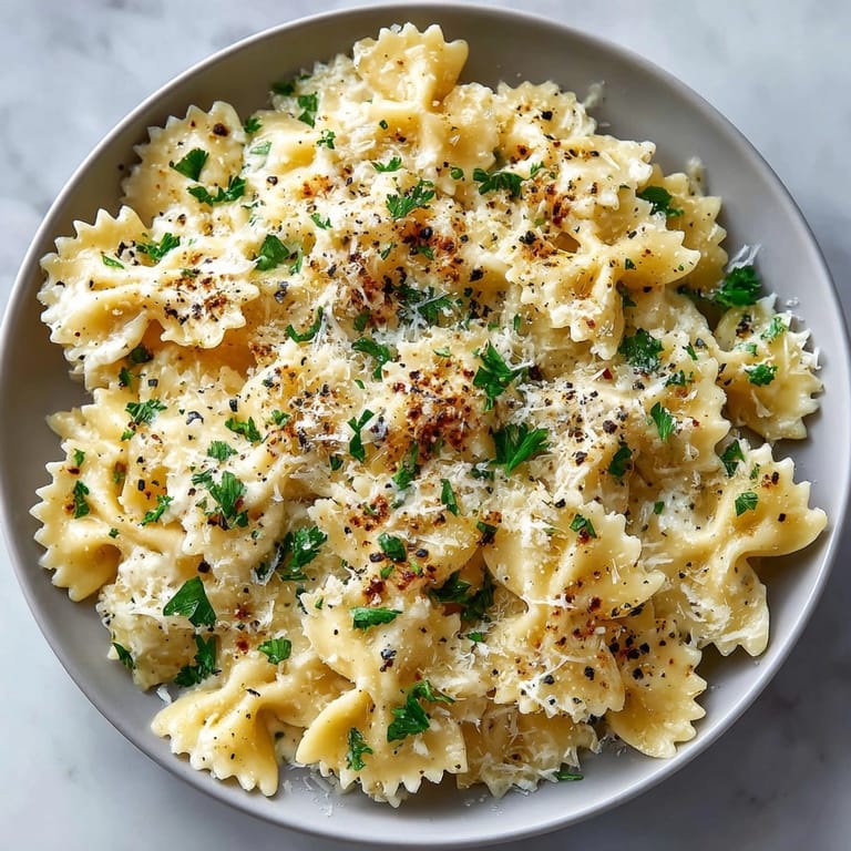 Close-up of al dente Creamy Garlic Parmesan Farfalle, sprinkled with fresh parsley and pepper.