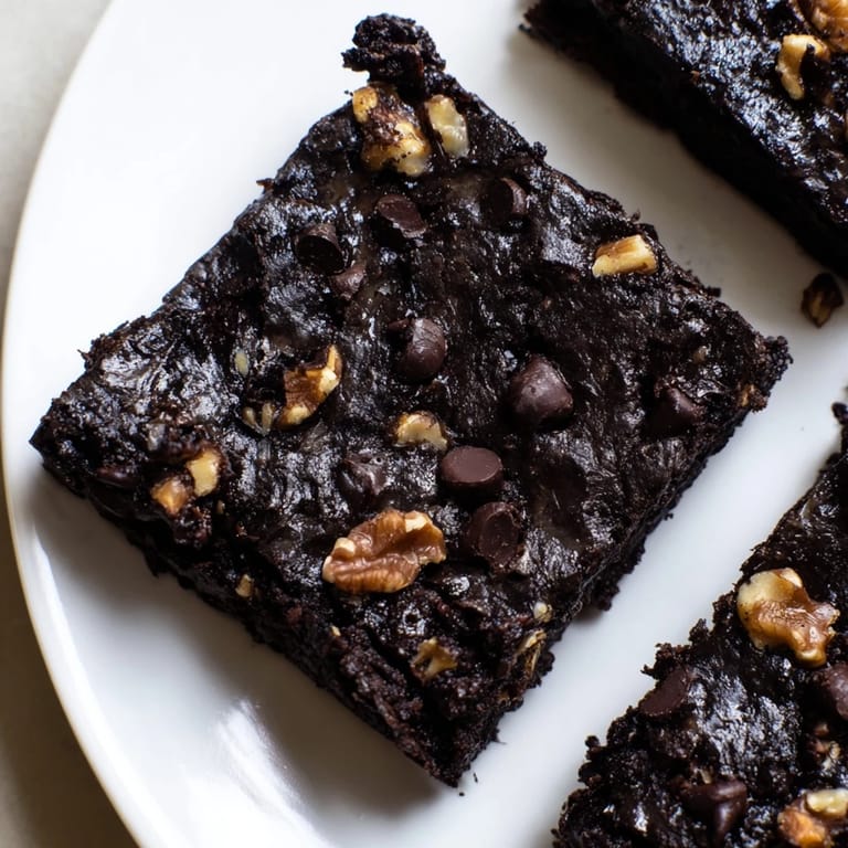 Warm Black Bean Brownies are freshly baked, with visible chocolate chips, promising a delightful treat.