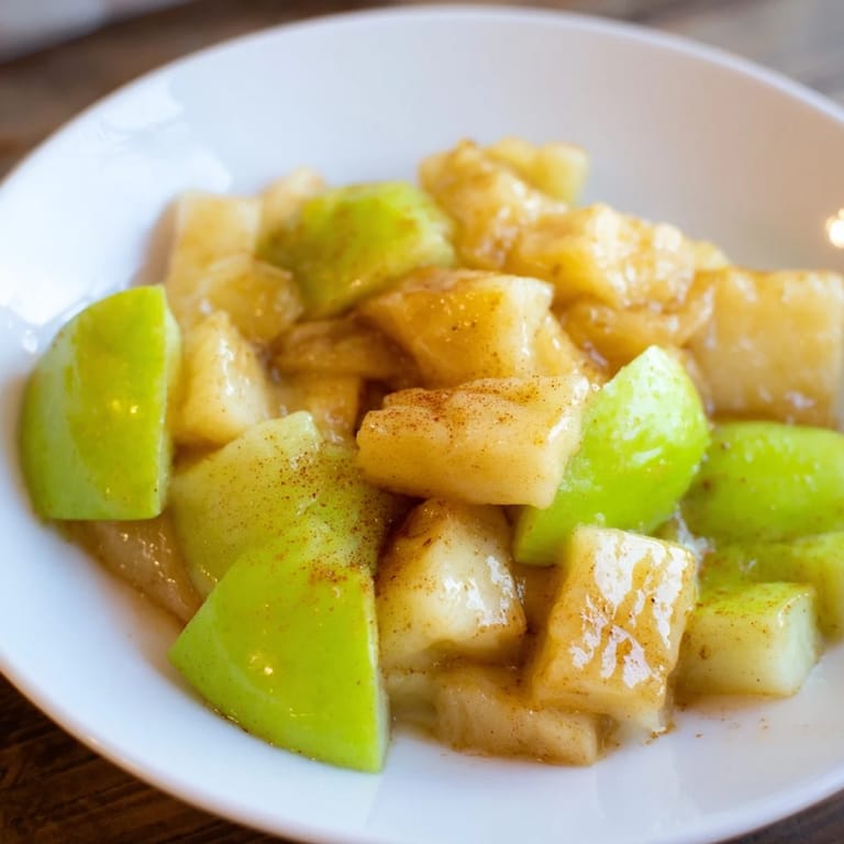 Steaming slow cooker stewed apples with cinnamon, honey, and tender, soft apple chunks in a bowl.