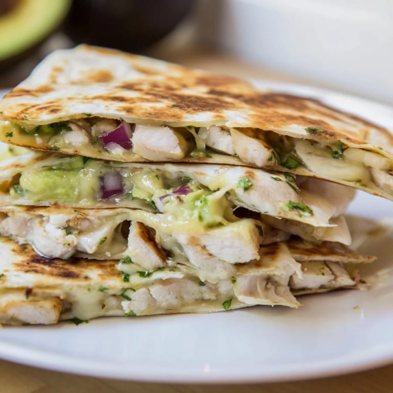 Crispy tortilla holding a flavorful Chicken Avocado Quesadilla, ready to eat with melted cheese.