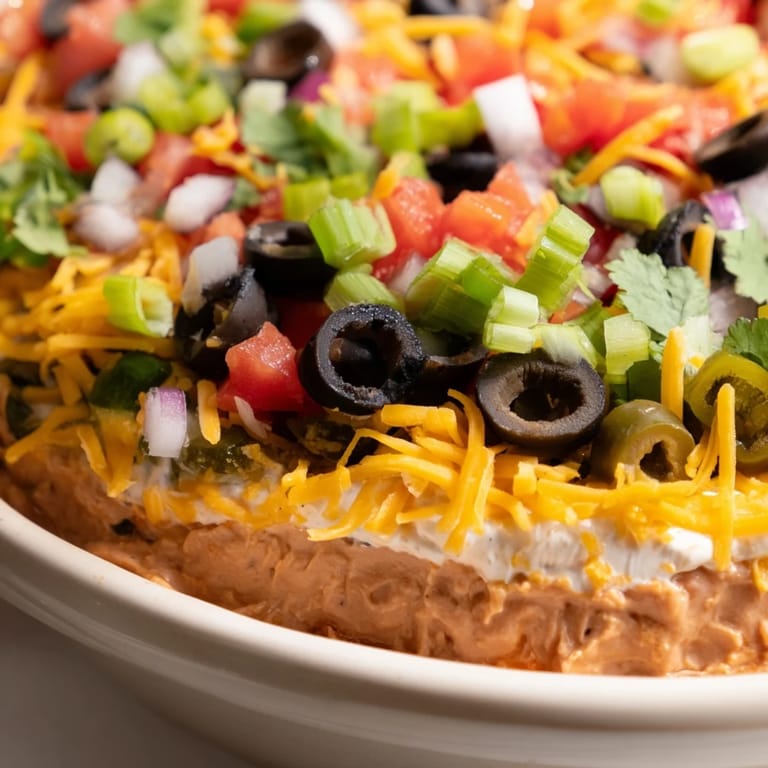 Serving the 4-Way Layered Dip with crispy tortilla chips at a festive party spread.