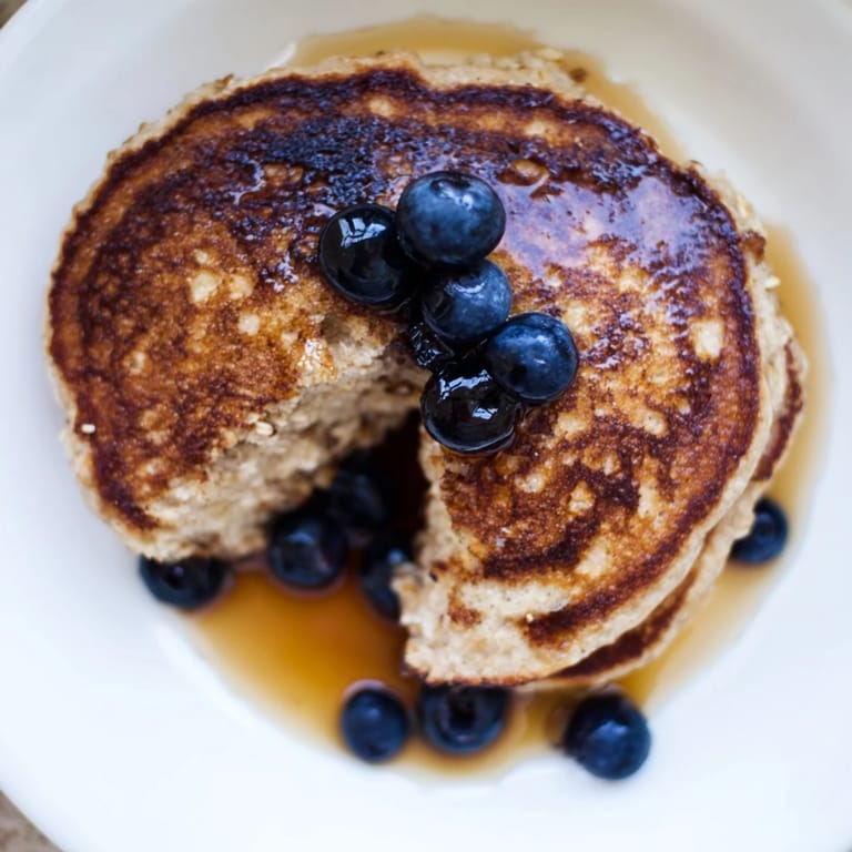 A close-up view of Banana Oat Pancakes reveals a tender crumb, perfect with a dollop of yogurt and berries.