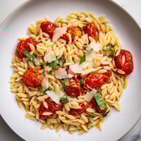 Golden, creamy Orzo Tomato Parmesan pasta dish with vibrant red cherry tomatoes and fresh basil.